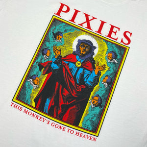 Close up of a white t shirt with red text reading "Pixies." Below the text is a design of a monkey dressed like a saint surrounded by cherubs and clouds. Below this design there is red text reading "This Monkey's Gone to Heaven"