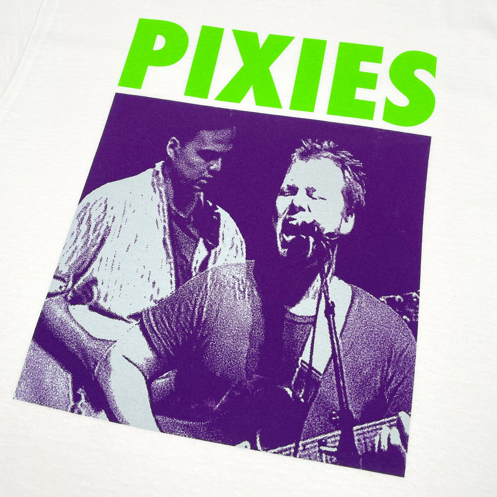 White Pixies t-shirt with green "Pixies" Logo and a purple photo of band performing against white background