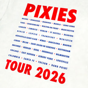 A white T shirt with red text at the top reading "PIXIES" and red text at the bottom reading "Tour 2026" in between the red text is blue text listing all the cities on the Pixies 2026 Tour.