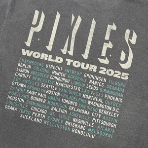 A close up of the back of a washed black tee shirt with off white text reading "Pixies world tour 2025" followed by alternating teal and off white text listing all tour locations.