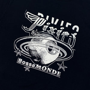 Close up of a black t shirt with white text logo reading "Pixies" followed by a white design of an eyeball with Saturn like rings and stars. Below is white text reading "Bossa Monde"